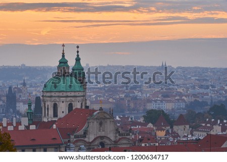  Cityscape of landscape Picture of the lesser town with dome of Saint Nicolas church in the Prague, in the morning just before sunrise in blue mood with orange sky.                              