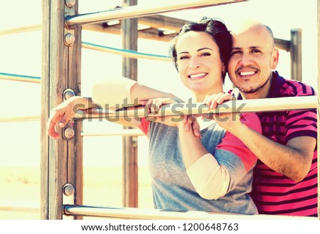 Portrait of happy man and woman standing together close to wall bars and smiling