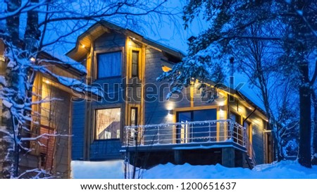Country house in winter. Two-storey mansion. Cottage illuminated with lights. Camping. Country trave. House in the forest. 