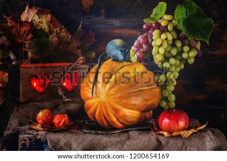 Halloween pumpkin and a rat on a wooden box among the autumn foliage