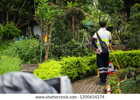 The surveyor makes measurements for the cadastre. Asian surveyor working in green summer park.