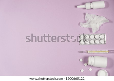 Treatment of colds and flu. Various medicines, a thermometer, sprays from a stuffy nose and a pain in a throat on a pink background. Copy space.
