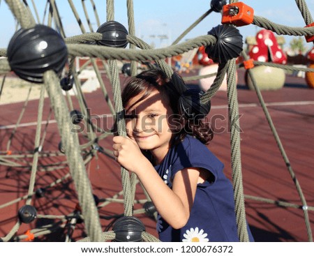 Beautiful girl playing on the playground in children's park.
