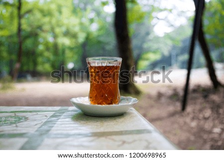 Eastern black tea in glass on a table in forest. Eastern tea concept. Armudu traditional cup. Green nature background. Selective focus