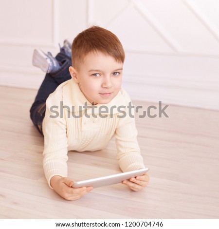 Cute boy. Computer tablet. play game, chat. Training. light interior.