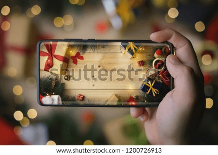 Hand Taking Picture of Christmas Decoration With Infinite Display Smartphone