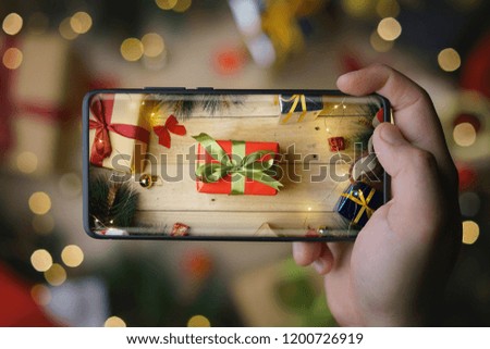 Hand Taking Picture of Christmas Present With Infinite Display Smartphone