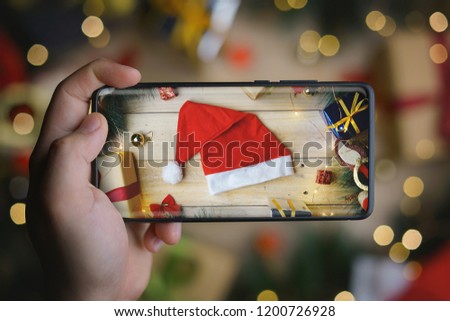 Hand Taking Picture of Santa Hat With Infinite Display Smartphone