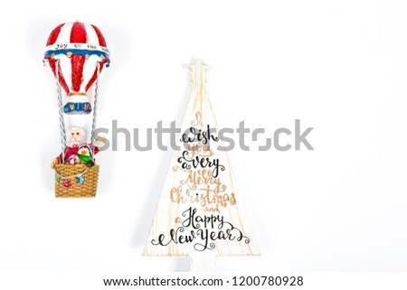 Santa Claus in Hot air balloon flight up to a wood white tree with Merry Christmas Happy new year written on, on white background. Place to write