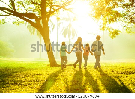 Happy Asian family holding hands walking over green lawn outdoor park, having quality time together. Royalty-Free Stock Photo #120079894