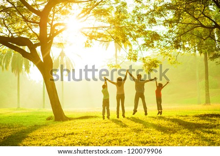Rear view of joyful happy Asian family jumping together at outdoor park