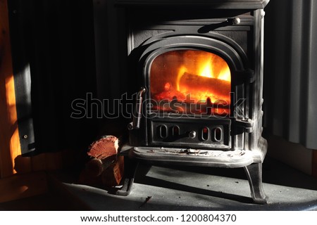 A black cast iron fire place with wood burning inside of it. Keeping warm concept image. 