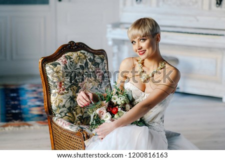 stylish bride with short hair with a big bouquet sits on the chair of the house
