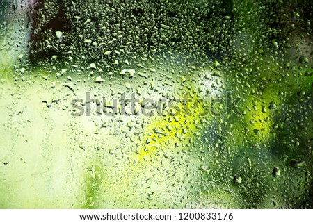 Rain falls on the glass, causing water drops.