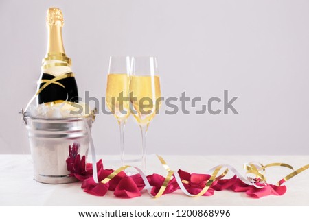Champagne bottle with glasses against a neutral background