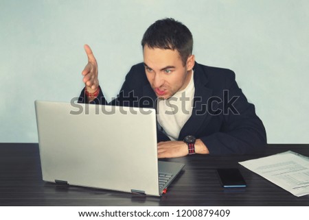 the young man freelancer programmer PC user with a disgruntled bitter angry expression on his face looking at the laptop in front of him by moving his hands aside. loss of profit and money