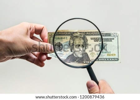 Expert with magnifying glass checks suspicious money. search watermarks on paper of the fake bills. magnifying glass, magnifier, magnifying lens, magnifying glasses, loupe