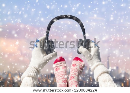 Women's feet in Christmas socks and headphones on the Manhattan background. New York city.  Winter concept.