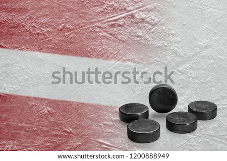 Hockey pucks and the image of the Latvian flag on the ice. Concept, hockey