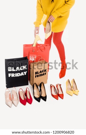 partial view of woman, shopping bags with black friday inscription and stylish female footwear isolated on white