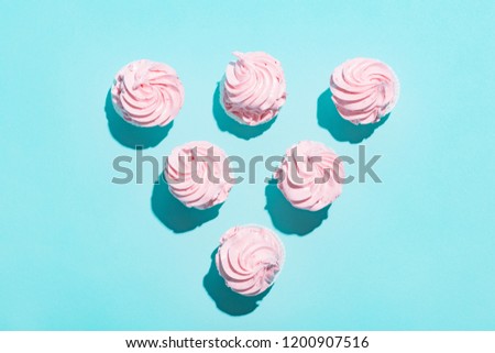 Triangle of pink muffins on blue background. Delicious cupcakes, sweet dessert.