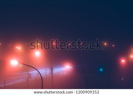 Neon lights of night city and motion traffic in fog. Retro colored image.
