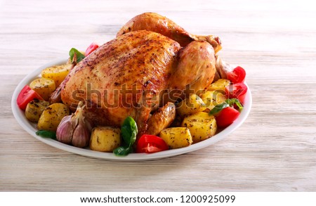 Whole roast spicy chicken with potatoes, on plate over wooden background Royalty-Free Stock Photo #1200925099