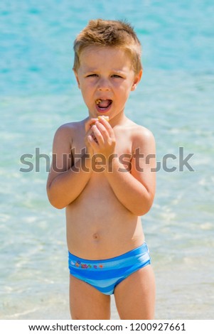 The boy eats a donut on the beach