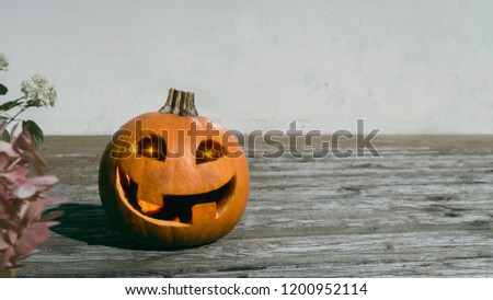 Halloween pumpkin with glowing eyes on the background of a white wall