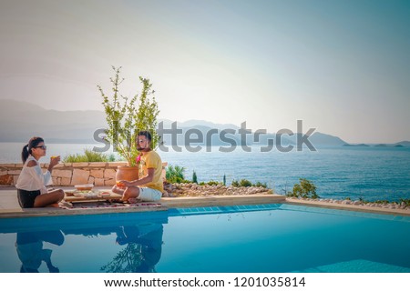 young couple man and woman by the pool having breakfast during vacation 