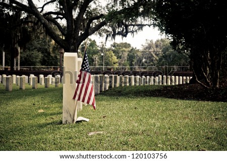Row of tombstones at Beaufort National Cemetery in South Carolina, with American Flag in ground of first grave site