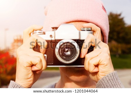 Young woman travel on vacation and using a camera to take photo outdoors at the park.