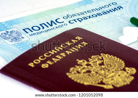 Close-up of Russian health insurance policy and Russian passport and a few pills on blue background Royalty-Free Stock Photo #1201052098