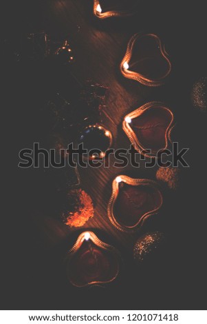 Beautiful Diwali diyas at night with flowers, lighting series and gifts, moody background