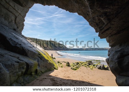 Cave on the sandy beach in Penbryn, Cardigan Bay, Wales. Taken on a sunny day when the beach was empty. Royalty-Free Stock Photo #1201072318