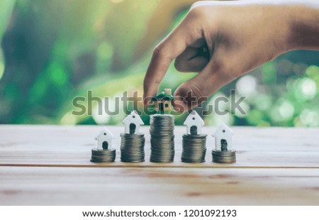 House placed on coins Men's hand is planning savings money of coins to buy a home concept concept for property ladder, mortgage and real estate investment. for saving or investment for a house,