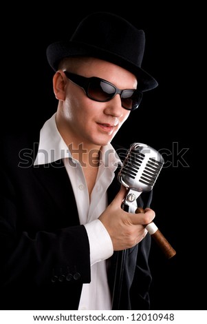 Singer with old-fashioned mic and black hat