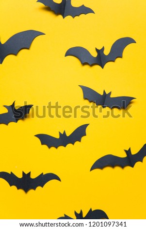 Halloween paper vampire bat decorations on an orange background.