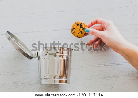 hand throwing cookie into a trash can, metaphor about website cookies and user tracking technologies Royalty-Free Stock Photo #1201117114