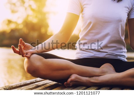 Young brunette woman practicing yoga on the beach at sunset