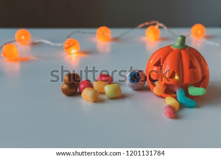 Orange pumpkin with  gummy worms in mouth. copy space, close up. Halloween party decoration. Trick or treat concept.
