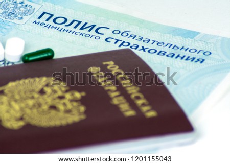 Close-up of Russian health insurance policy and Russian passport and a few pills on blue background Royalty-Free Stock Photo #1201155043