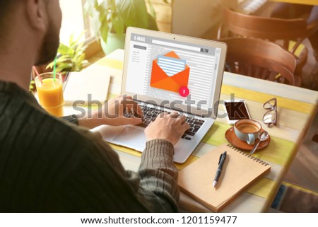 Young man with laptop checking an email in cafe Royalty-Free Stock Photo #1201159477