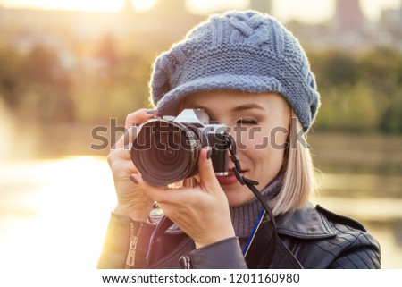 stylish blonde woman photographer takes pictures of autumn forest at sunset
