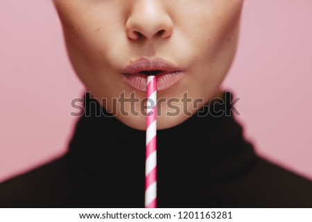 Close up of woman with straw in pink background. Face of female model with a straw. Royalty-Free Stock Photo #1201163281