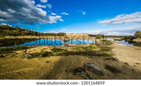 Sandy hills. Lake in the Sandy canyon. Warm colors background. Yellow sandstone textured mountain, white thin sand dune, bright sky. Sunshine landscape