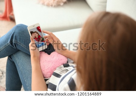Young woman with mobile phone using website for online dating at home