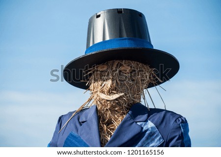 portrait of scarecrow with head in straw on blue sky background