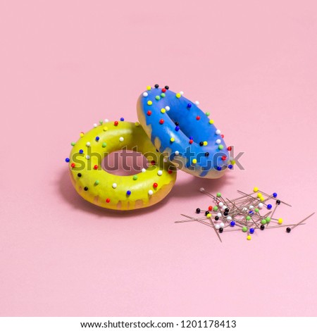 Humorous imitation of donuts from painted bagels with multi-colored pins. Artificial object that mimics natural forms. Joke on theme of food. Minimal style. Creative idea and fantasy. Modern pop art