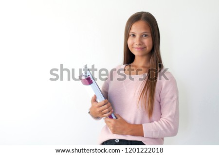 Girl child standing in front of white wall. Back to school concept. Girl child holding books in hand.